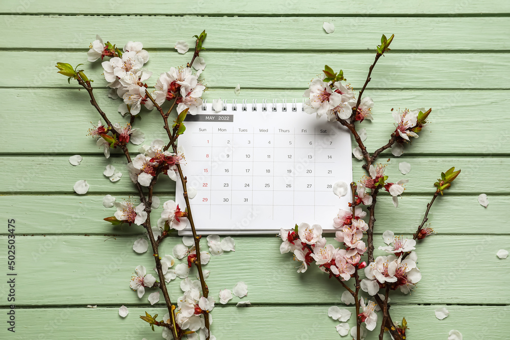 Beautiful blooming spring branches and calendar on color wooden background