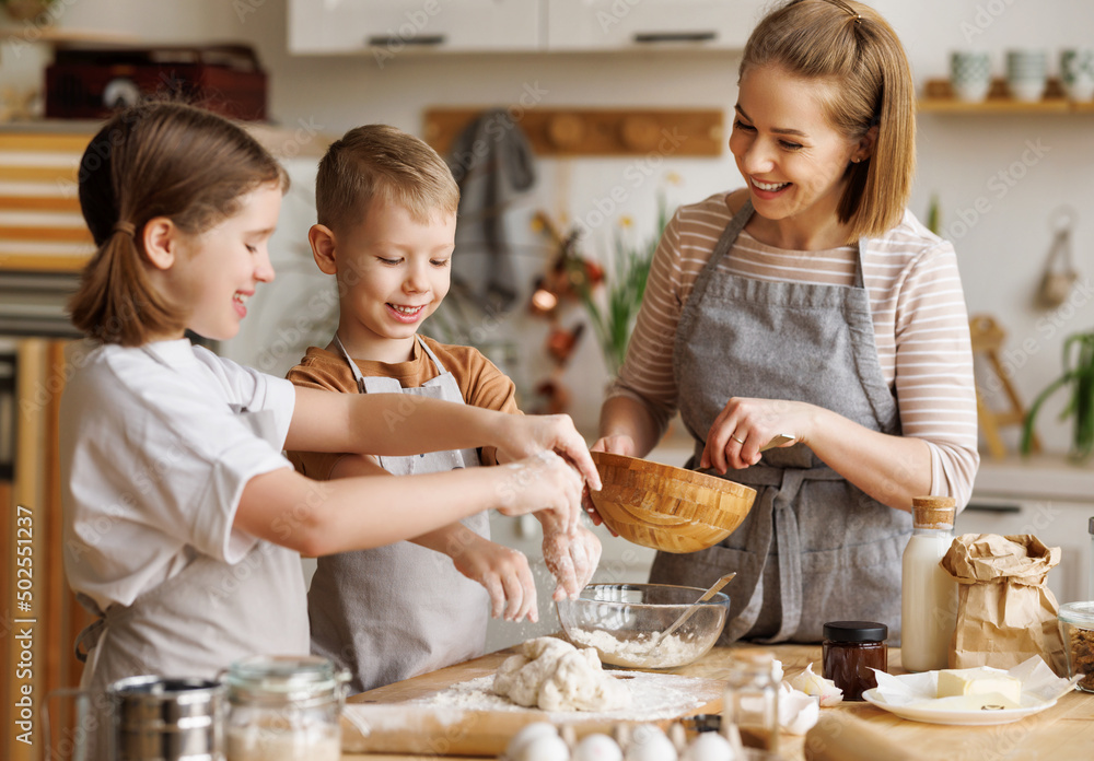 Happy woman and cute children cooking together in kitchen