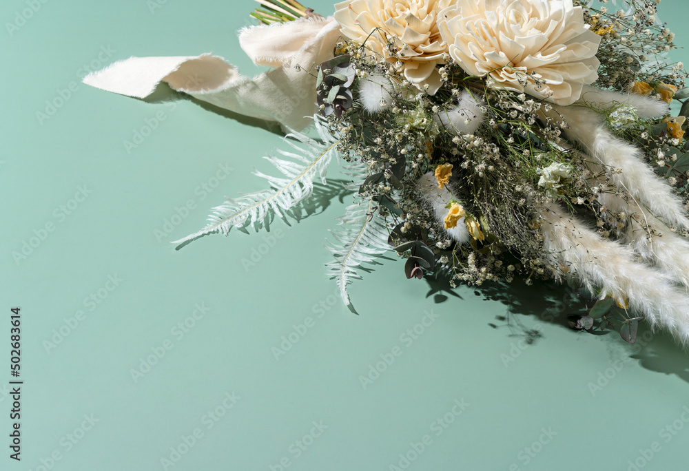 Bouquet of dried flowers placed on green background.