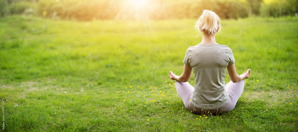 Woman sitting in active wear in lotus position in nature.