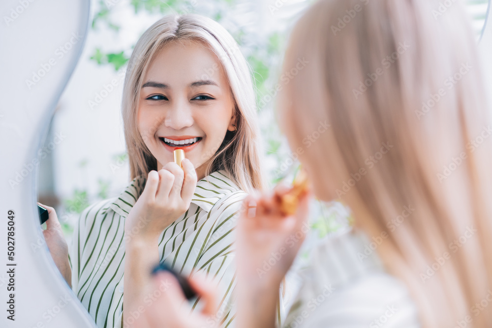 亚洲年轻女性在镜子前涂口红