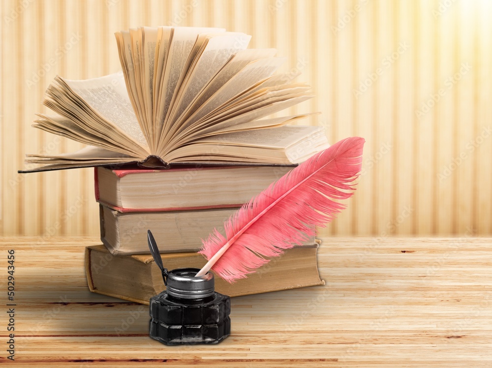 Stack of old  antique books, inkwell with quill pen.