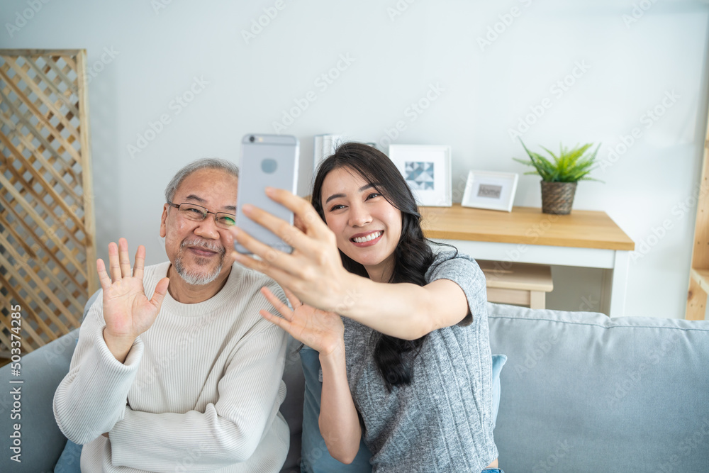 亚洲可爱的家庭，年幼的女儿用手机与年长的父亲自拍。