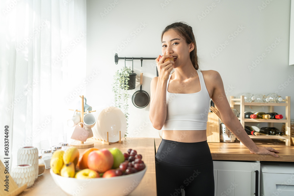 在家里的厨房里拿着红苹果的亚洲美女