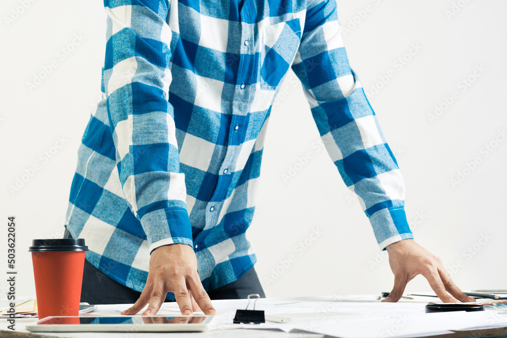 Architect standing near desk with blueprints