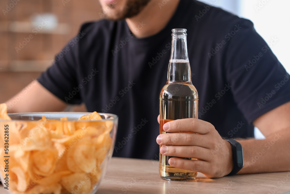 Handsome man drinking beer in kitchen