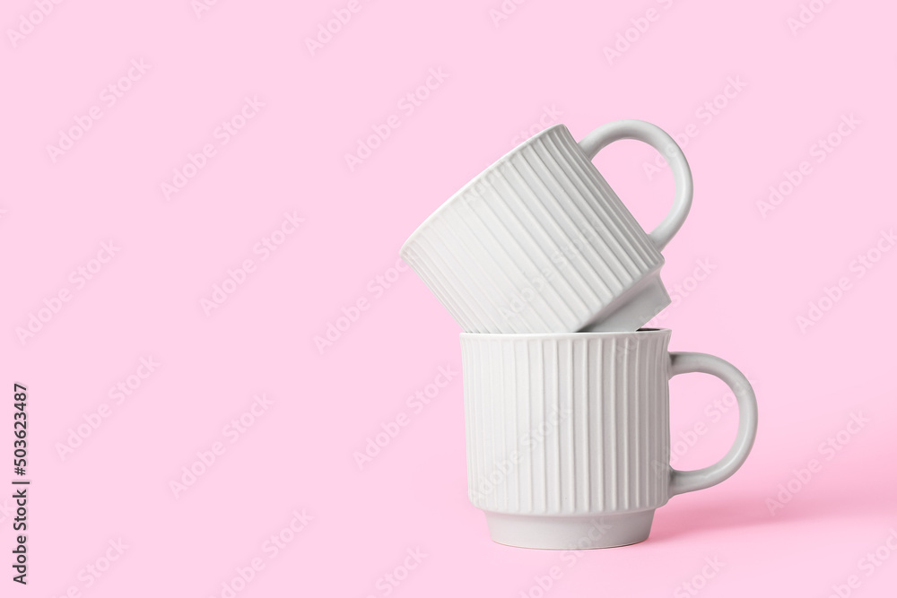 Ceramic cups on pink background