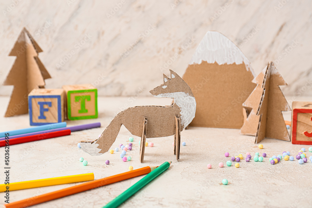 Handmade cardboard toys and stationery supplies on light background