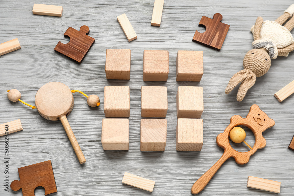 Cubes with baby toys on grey wooden background