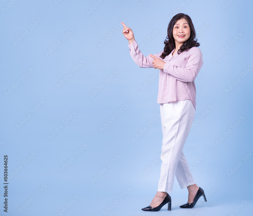 Full length image of middle aged Asian woman on blue background