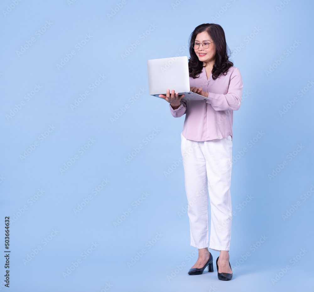 Full length image of middle aged Asian woman on blue background