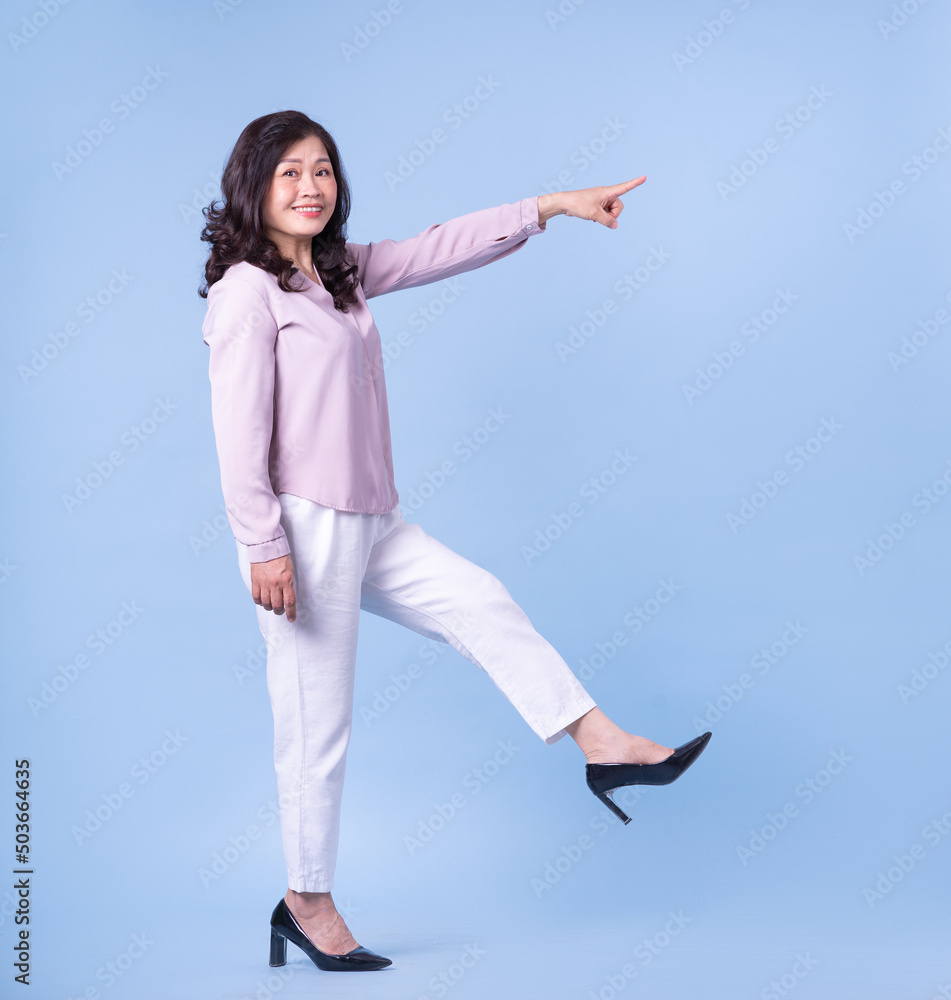 Full length image of middle aged Asian woman on blue background