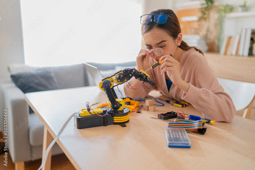 聪明的亚洲女程序员学习STEM中的机械臂ai编码电子板电缆，STEAM she