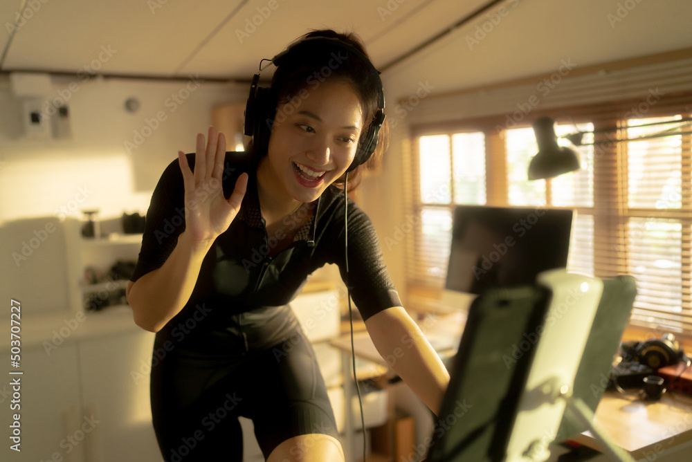 Female Asian cyclist, She is exercising at home. She rides a bike simulator.