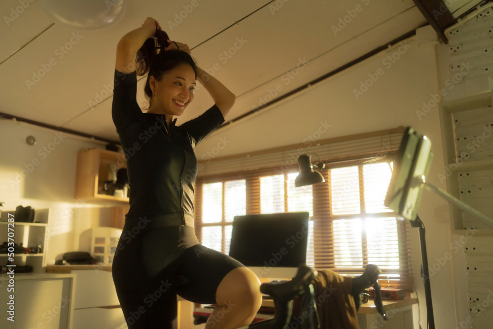 Female Asian cyclist, She is exercising at home. She rides a bike simulator.