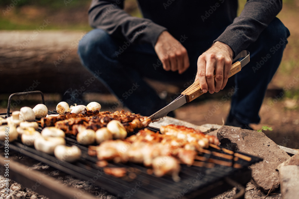 一名男性烧烤、烤肉和蔬菜的特写。