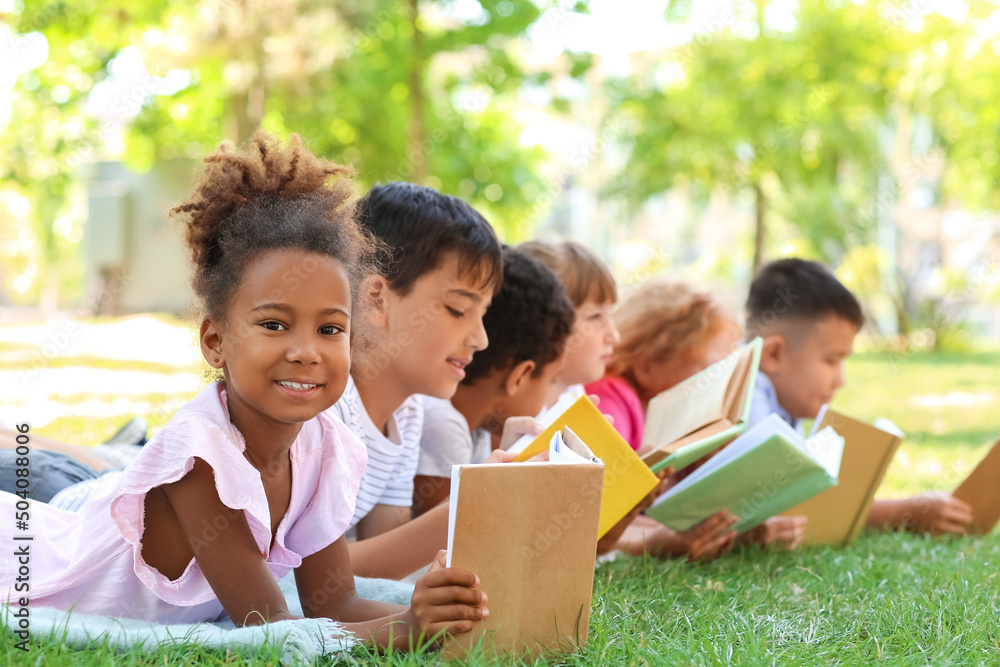 Cute little children reading books in park