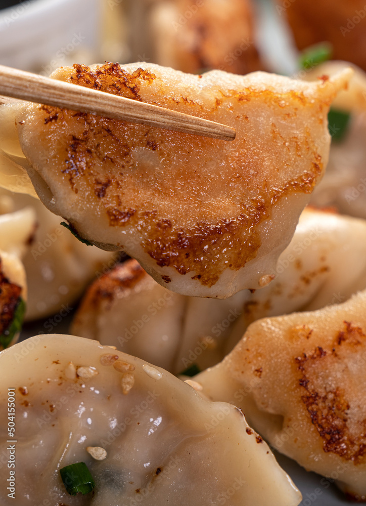 灰色桌子背景上放着酱油的锅里煎饺子饺子饺子。