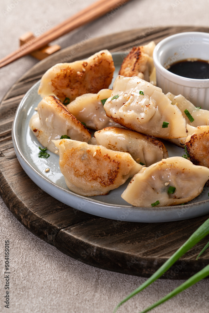 灰色桌子背景上放着酱油的锅里煎饺子饺子饺子。