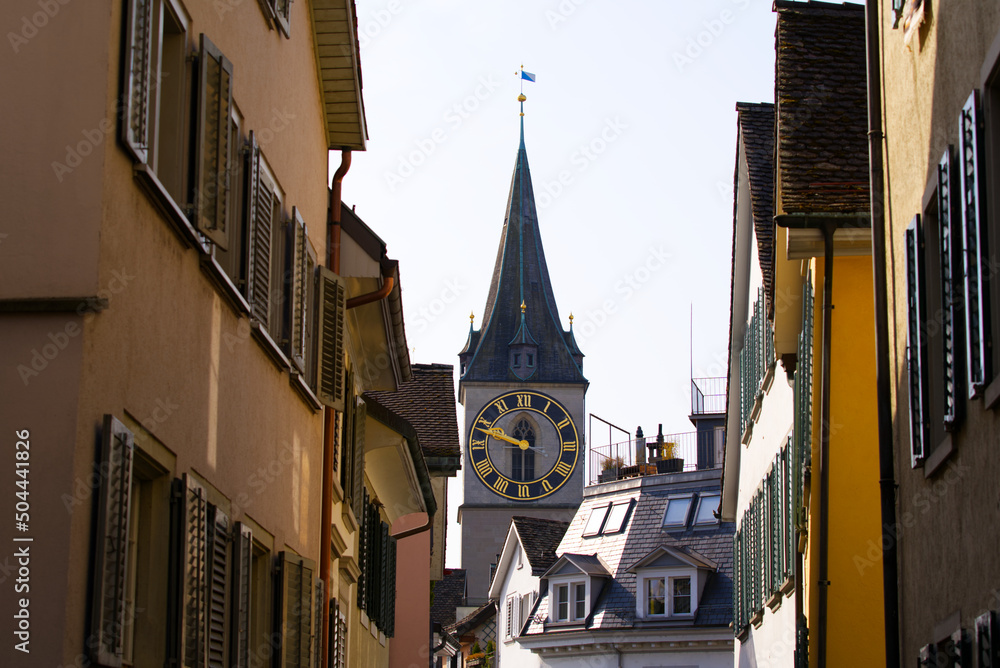 Facades of historic houses at the old town of Zürich with clock tower of St. Peter church in the bac