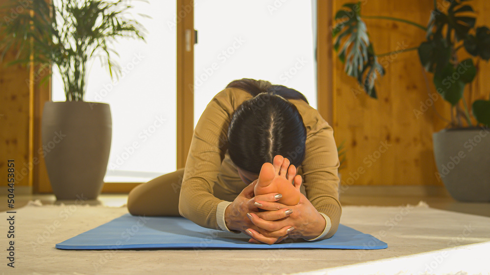 PORTRAIT: Front view of Asian woman practicing seated head to knee yoga posture