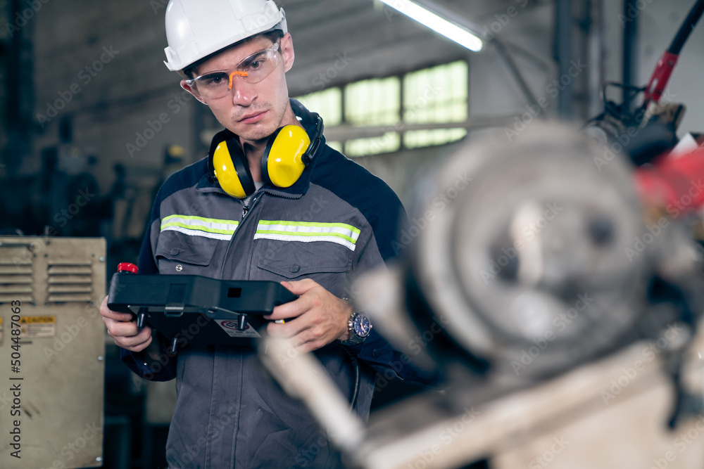 Young factory worker working with adept robotic arm in a workshop . Industry robot programming softw