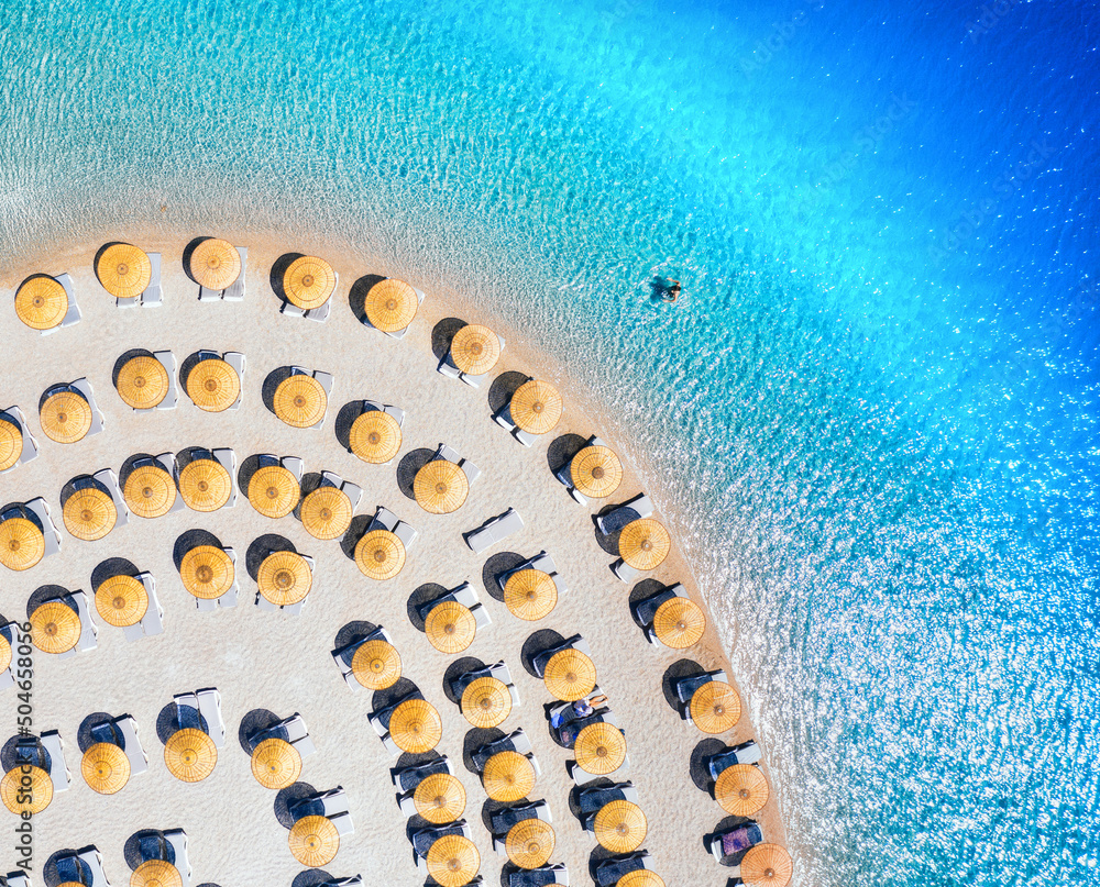 Aerial view of blue sea, empty sandy beach with sun beds and umbrellas at sunset in summer. Blue lag