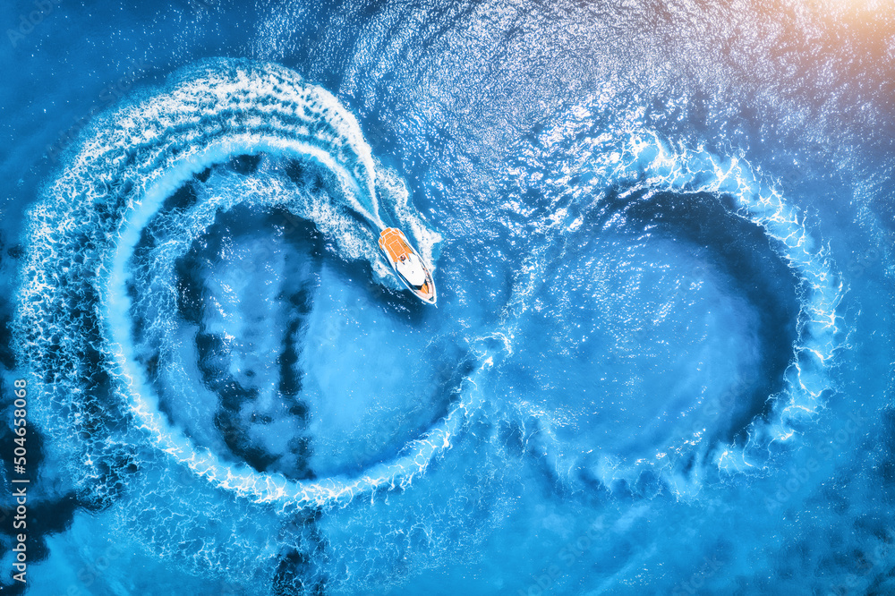 Aerial view of the speed boat in clear blue water at sunset in summer. Top view from drone of fast f