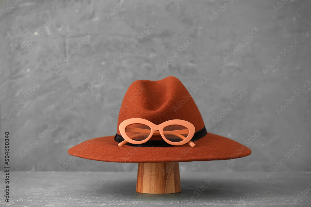 Felt hat and glasses on grey background