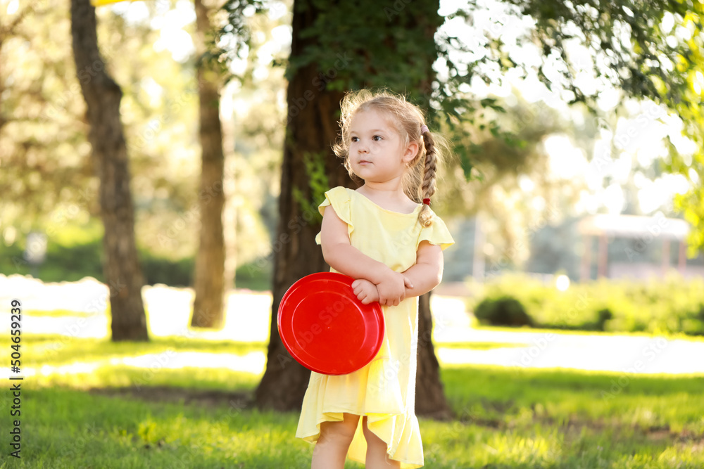 Cute little girl in yellow dress playing frisbee in park