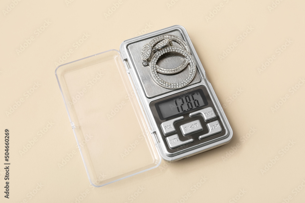 Jewelry scales with earrings on beige background