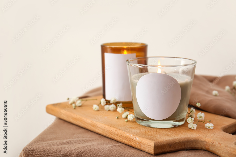 Holders with burning candles and flowers on table, closeup