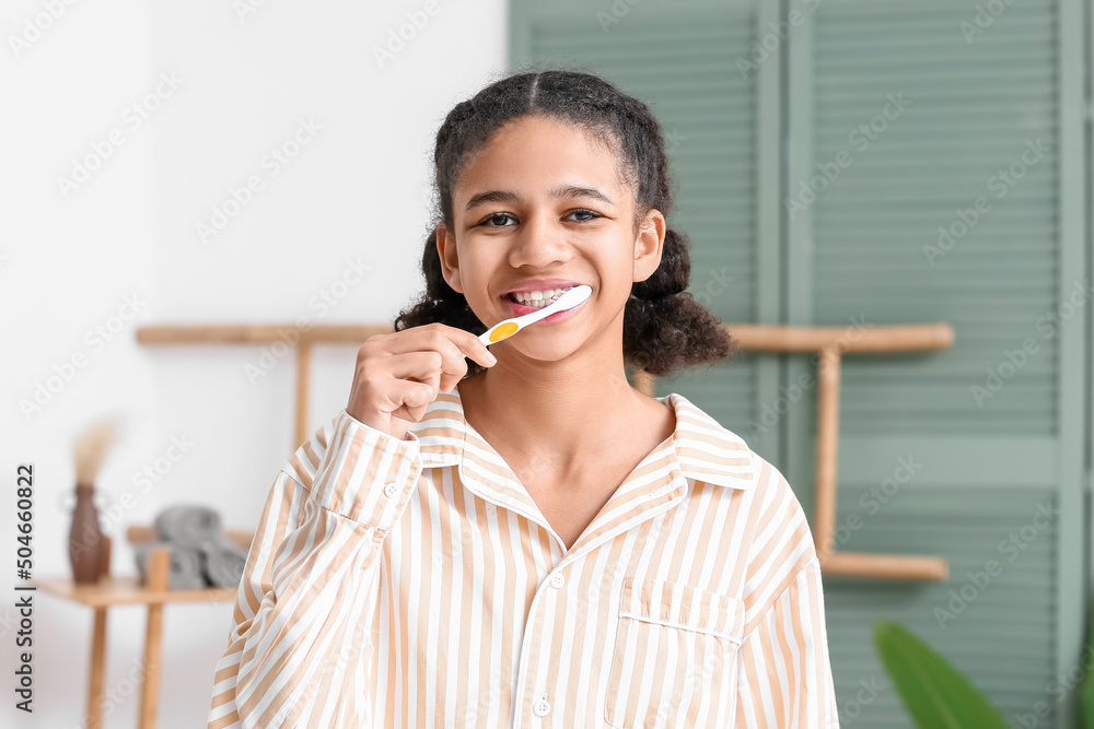 African-American teenage girl brushing teeth in bathroom