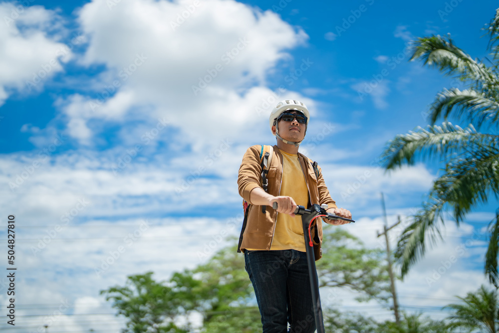 一名亚洲男子骑着电动滑板车上班。