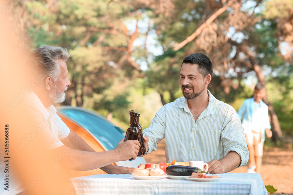 Handsome man drinking beer with his father at barbecue party on summer day