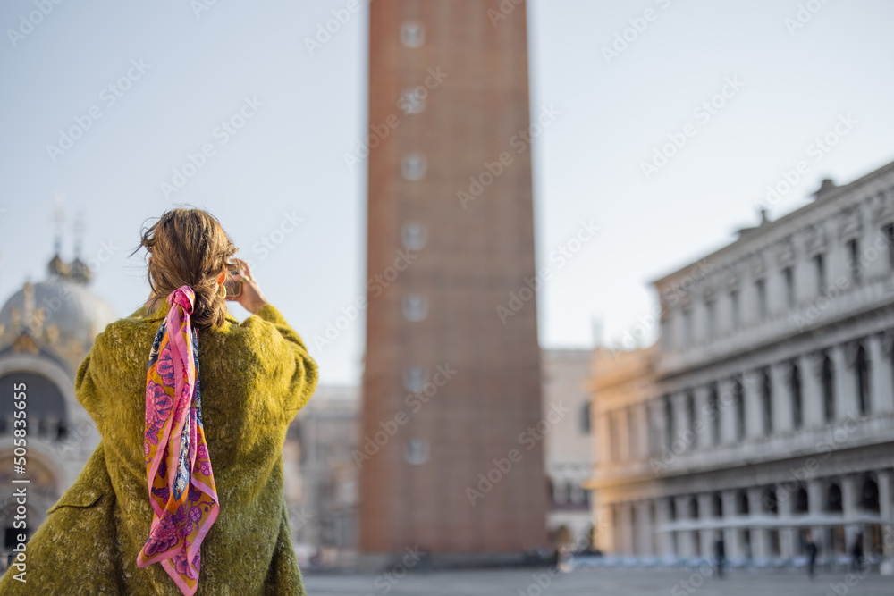 年轻女子在威尼斯著名的圣马可大教堂钟楼拍照。参观的概念