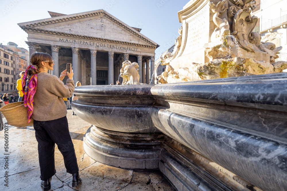 Young female traveler photographing famous Panthenon temple and fountain in Rome. Concept of happy v