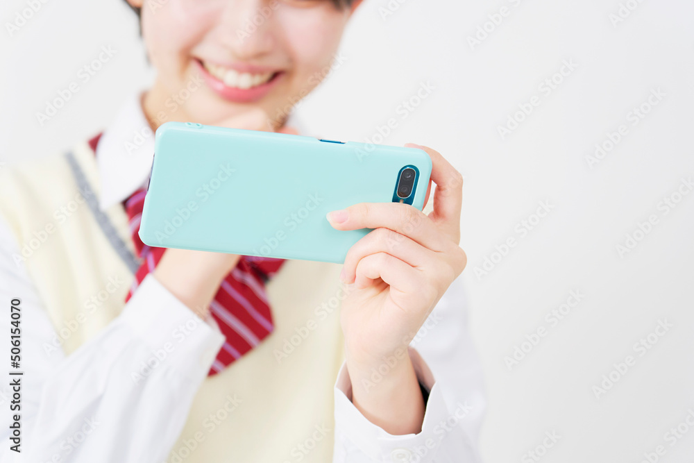 白背景でスマホを見る女子高生　手元