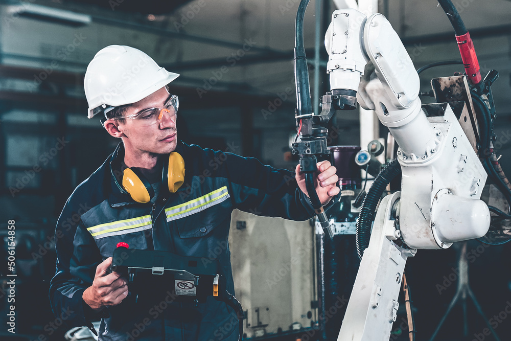 Young factory worker working with adept robotic arm in a workshop . Industry robot programming softw