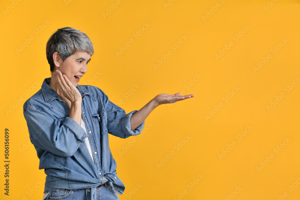 Middle aged Asian woman 50s showing empty copy space on the open hand palm for text or product isola