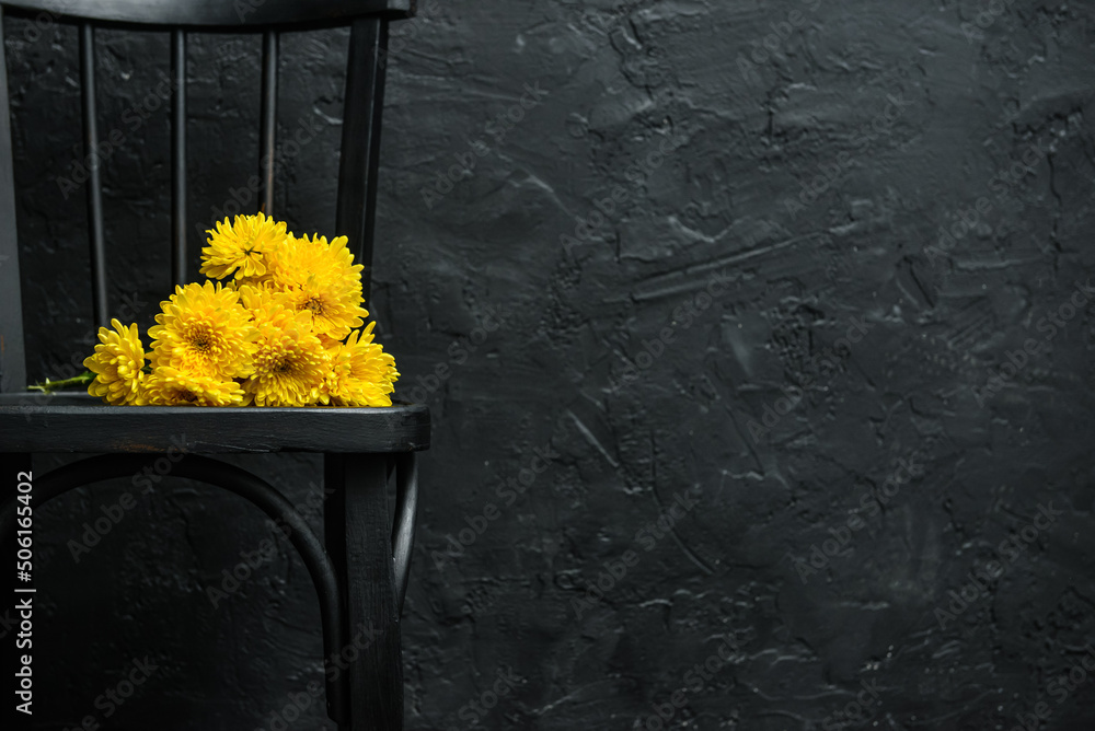 Black chair with yellow flowers near dark wall