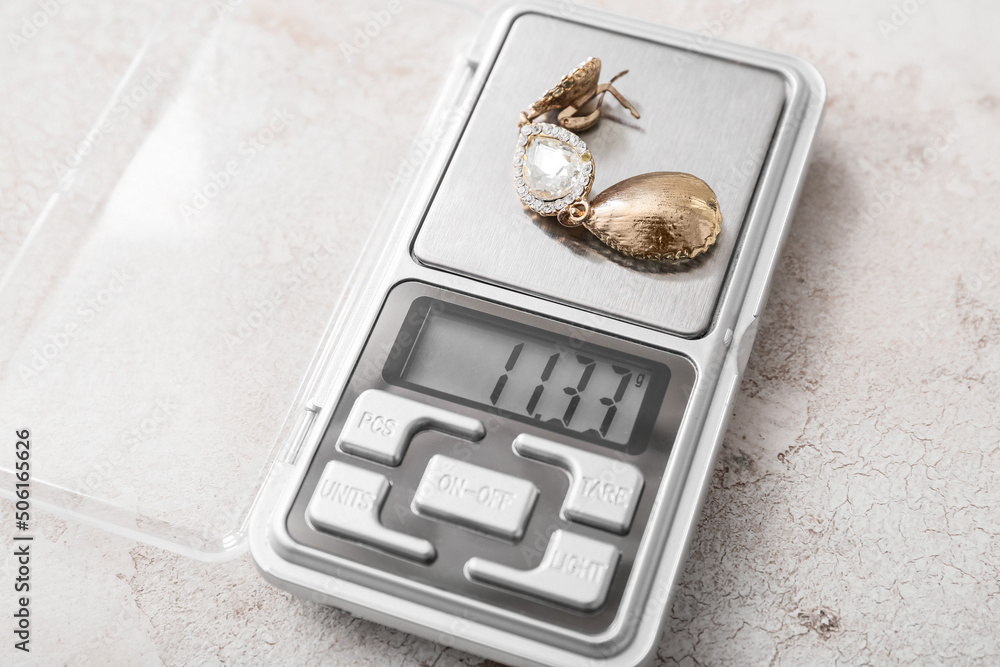 Jewelry scales with earring on light background