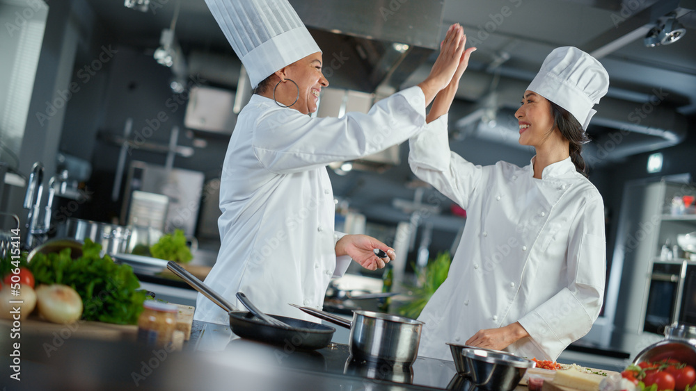 Restaurant Kitchen: Portrait of Asian and Black Female Chefs Preparing Dish, Tasting Food, Doing Hig