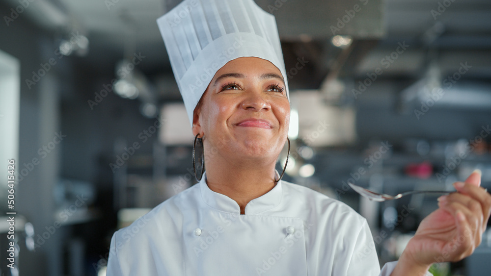 Restaurant Kitchen: Portrait of Black Female Chef Preparing Dish, Tasting Food and Enjoying it. Prof