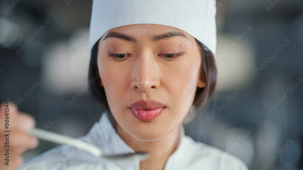 Restaurant Kitchen: Portrait of Asian Female Chef Preparing Dish, Tasting Food and Enjoying it. Prof