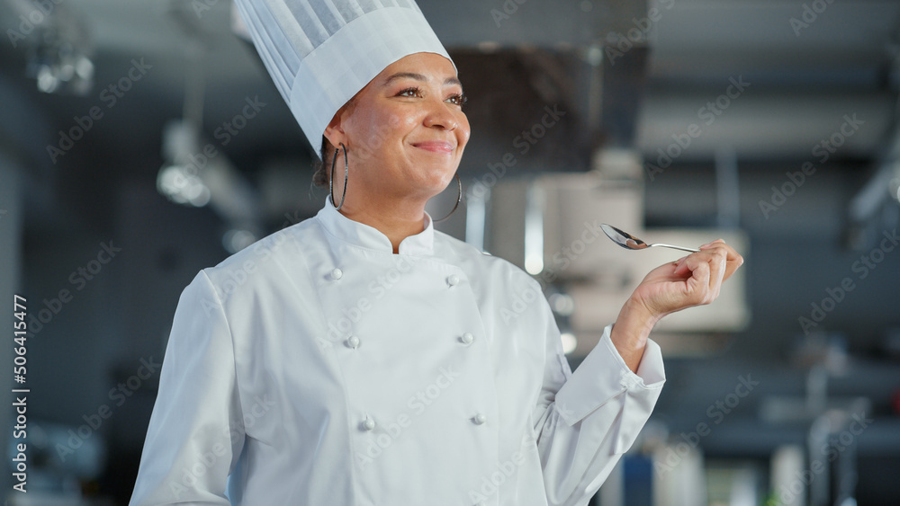 Restaurant Kitchen: Portrait of Black Female Chef Preparing Dish, Tasting Food and Enjoying it. Prof