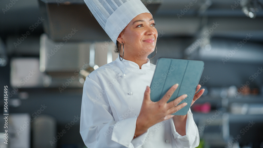 餐厅厨房：黑人女厨师烹饪美味正宗的食物，使用数字平板电脑