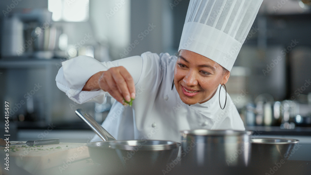 Restaurant Kitchen: Black Female Chef Fries Uses Pan, Seasons Dish with Herbs and Spices, Smiles. Pr