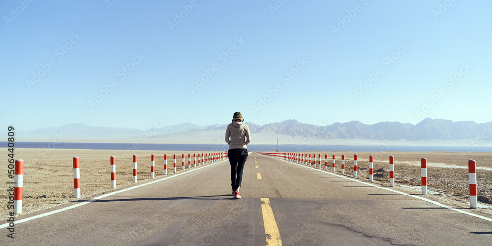 亚洲女游客在空旷的公路上走向湖泊