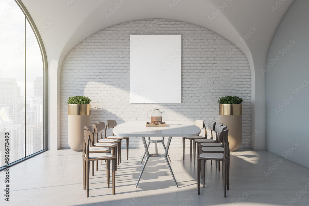 Blank white poster on brick wall in stylish dining area of modern apartment with white table surroun